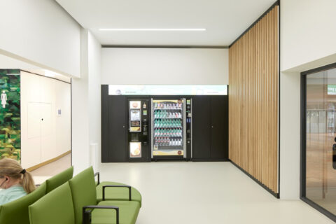 Snack- und Getränkeautomaten mit Holzlamellenwand und Sitzbereich – Servicezone in der Besucherwartezone Pier Ost.