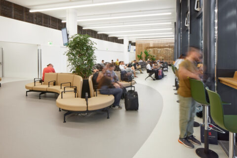 Runde Sitzinseln mit Pflanzen, kombiniert mit Reihenbestuhlung und Arbeitsplätzen in der Besucherwartezone.