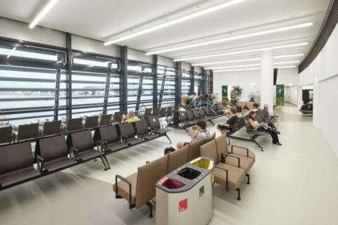 Besucherwartezone im Pier Ost des Flughafens Wien mit Reihenbestuhlung, Panoramafenstern zum Rollfeld und moderner Abfalltrennung.