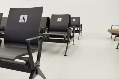 Barrierefreie Sitzplätze in der Besucherwartezone des Pier Ost am Flughafen Wien, gekennzeichnet mit Rollstuhlsymbol für inklusives Design.