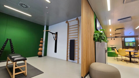 Sportzone mit Sprossenwand, Fitnessgeräten und grünen Wänden – aktiver Pausenbereich im Aufenthaltsraum des Flughafens.