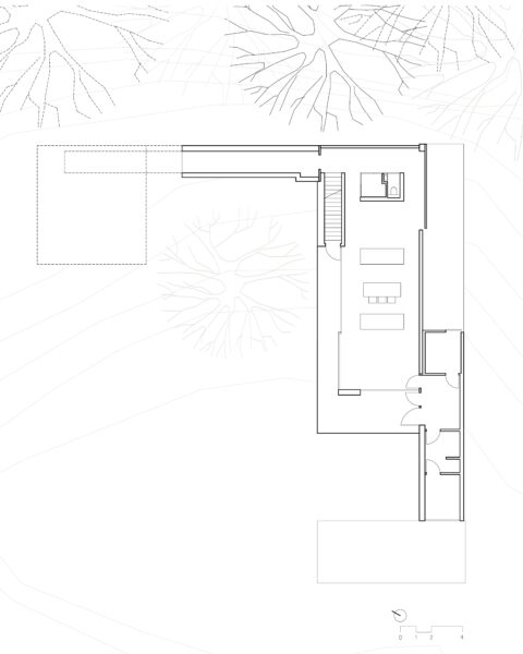 Grundriss des Erdgeschosses eines Gebäudes in L-Form. Der Plan zeigt einen offenen Wohn- und Essbereich mit Küche, eine Treppe, die ins Obergeschoss führt, sowie Nebenräume mit Bädern. Im Hintergrund sind schematisch Bäume und Geländelinien eingezeichnet.