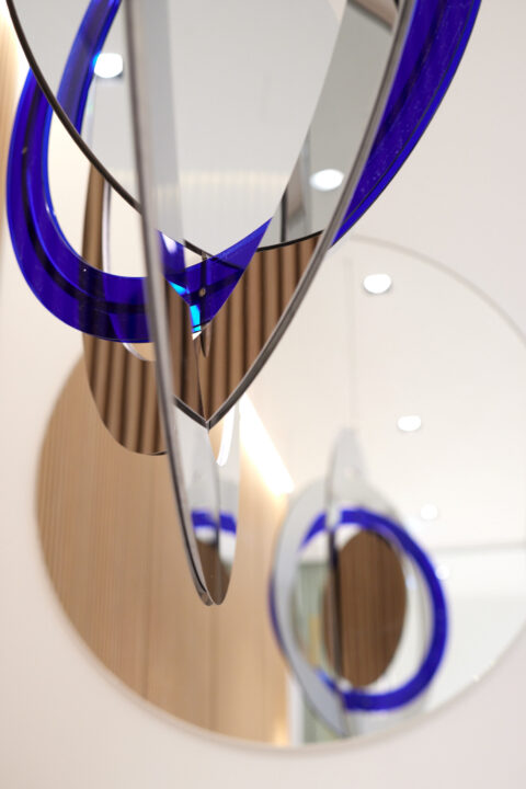 Detailansicht der Glas- und Spiegelelemente, die mit blauen Akzenten das Raumgefüge der Hypo Tirol Wien strukturieren.