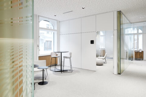 Helles Bank-Interior mit Glaswänden, modernen Loungemöbeln und flexiblen Beratungsbereichen für eine offene, transparente Atmosphäre.