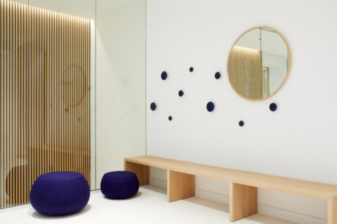 Moderne Garderobe mit Holzbank, runden Wandhaken, Spiegel und Design-Elementen aus Glas und Holz – funktionale Architektur mit Stil.