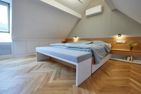 Schlafzimmerausbau Wien: modernes Bett mit integrierten Möbeln, Holzdetails und minimalistischer Gestaltung