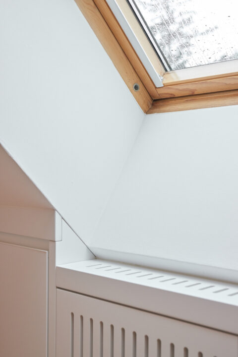 Dachgeschossausbau Wien mit Dachflächenfenster, minimalistischen Einbaumöbeln und klaren Linien, lichtdurchflutetes Interieur