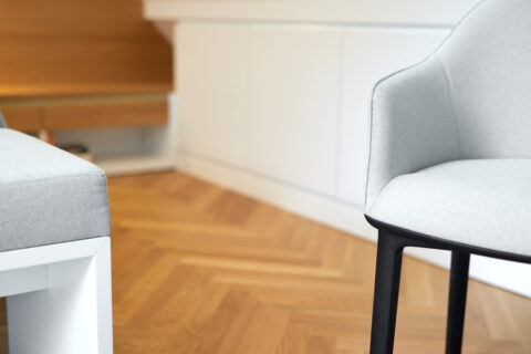 Moderner Dachausbau in Wien mit Parkettboden im Fischgrätmuster, grauen Polsterstühlen und maßgefertigten weißen Einbauten