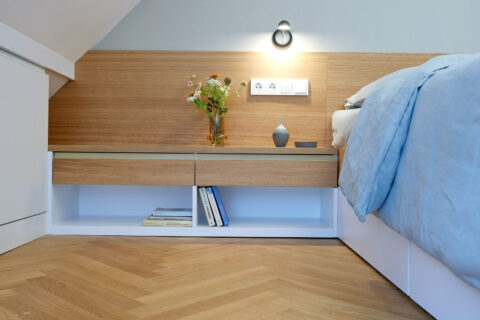 Schlafzimmer im Dachgeschoss Wien mit Holzvertäfelung, integrierten Nachttischen und minimalistischen Details