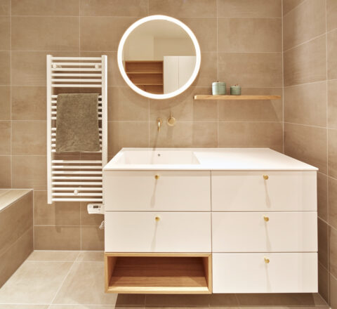 Bad mit weißem Waschtisch, Schubladen und rundem Spiegel – moderne Architektur in klaren Linien.