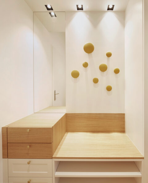Eingangsbereich mit Holzbank, Spiegelwand und runden Garderobenhaken, modernes minimalistisches Interior.