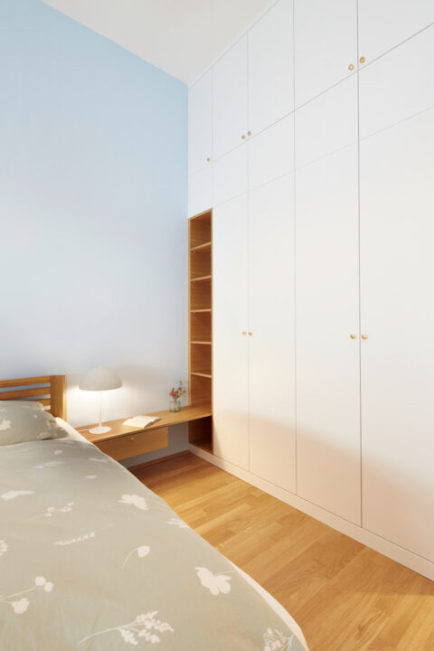 Schlafzimmer mit Einbauschrank in Weiß, Holzboden und maßgefertigter Nische – klare, reduzierte Architektur.