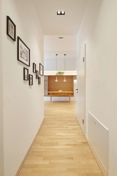 Flur mit Bildergalerie und Blick in den offenen Wohn- und Küchenbereich – moderne Architektur mit klaren Linien.