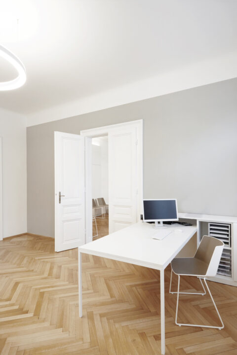 Doctor’s office with white desk, modern chair, and subtle gray wall design.