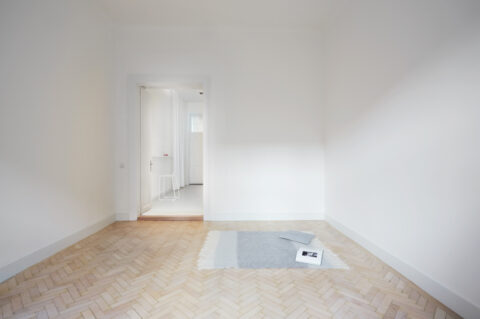 Heller Wohnraum mit Parkettboden, Blick in den Durchgang zur Küche.