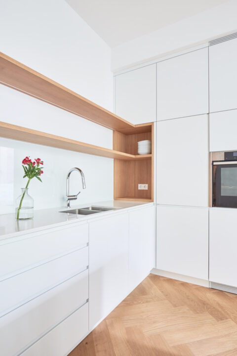 Detailansicht der Küchenspüle mit Holzregal und weißer Front