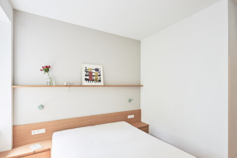 Schlafzimmer mit Holz-Nachttischen, grauer Wand und Bilderleiste