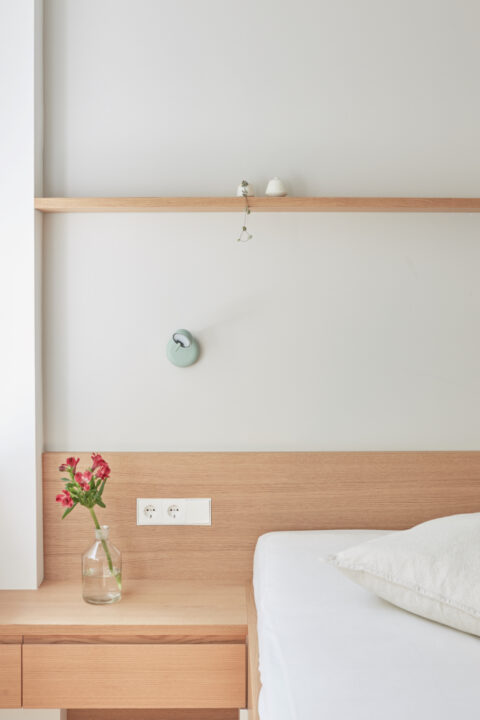 Detailaufnahme eines Nachttisches mit Vase und Holzrückwand