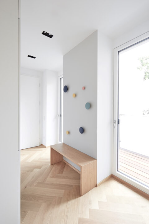 Garderobenbereich mit bunten Wandhaken und Sitzbank