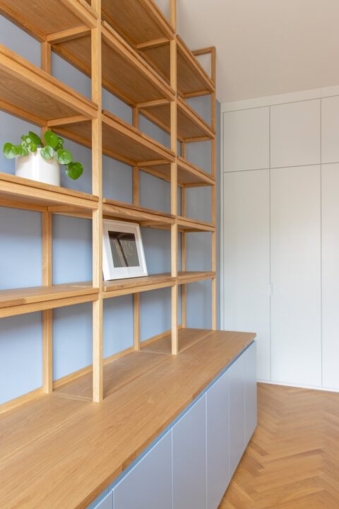 Offenes Holzregal mit Büchern und Pflanzen, vereint Funktionalität und Wohnlichkeit in einem klaren, zeitlosen Design.