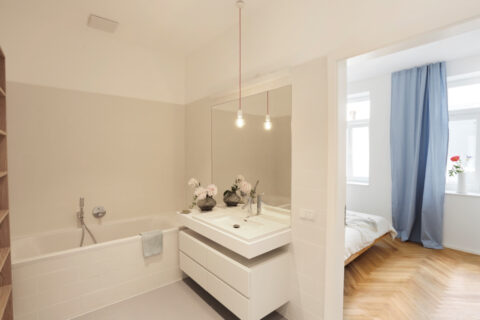 Badezimmer mit Badewanne, großem Spiegel und weißem Waschtisch, minimalistisches Design.