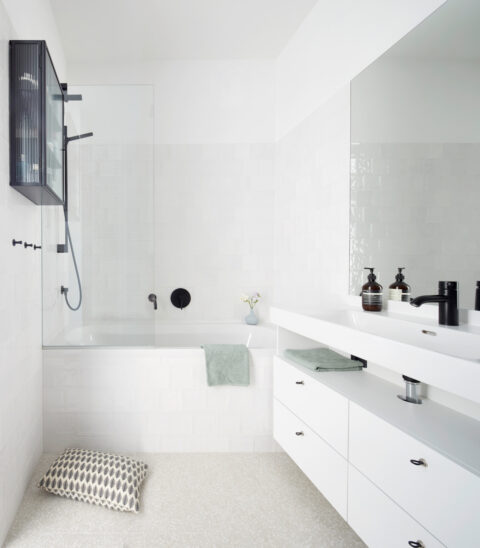 Modernes Badezimmer mit Badewanne, großem Spiegel und weißen Einbaumöbeln