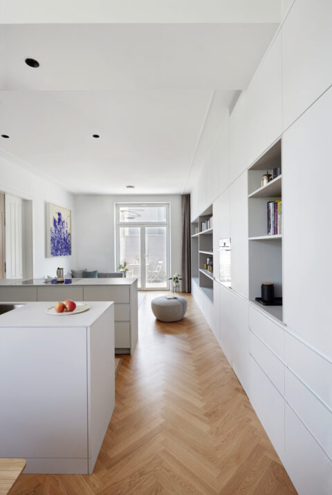 Moderne weiße Küche mit Kochinsel, Einbauschränken und großem Fenster