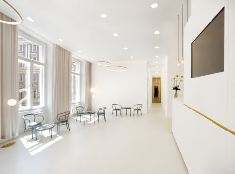 Heller Wartebereich der Zahnklinik mit Sitzmöbeln und großen Fenstern.