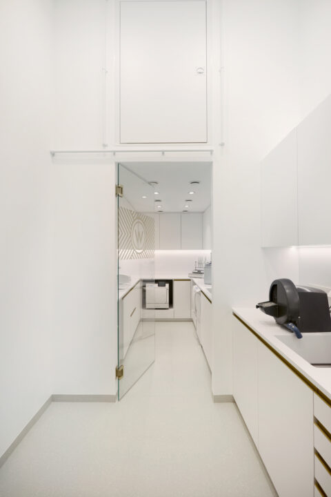 Weiß gestalteter Nebenraum mit Arbeitsflächen und Stauraum.