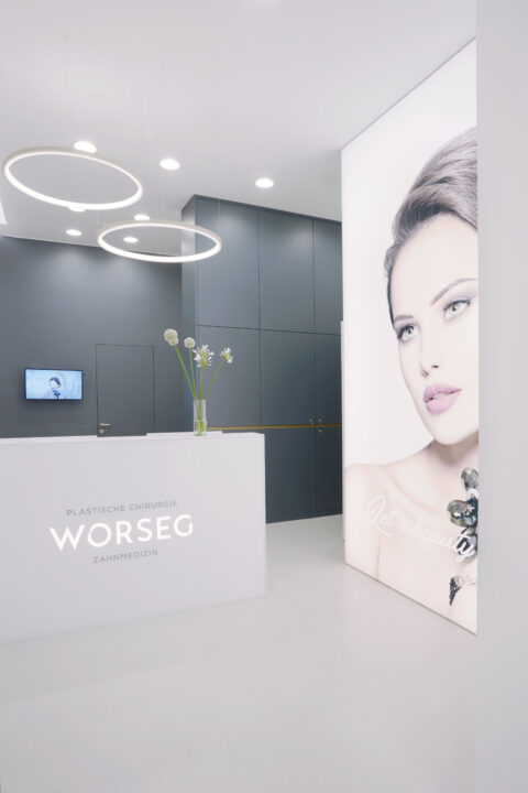 Moderne Rezeption mit beleuchtetem Logo „WORSEG“ und großflächigem Porträt einer Frau an der Wand.