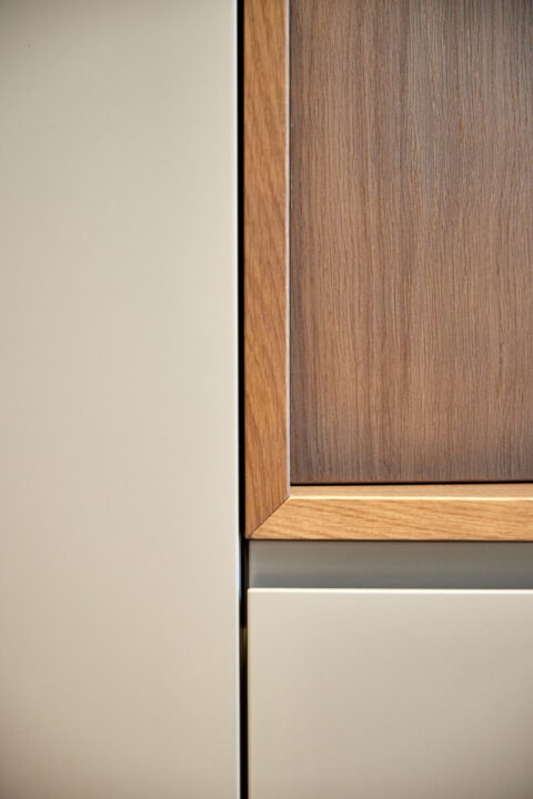 Detailaufnahme einer Schrankfront mit Holzrahmung und matten Oberflächen.