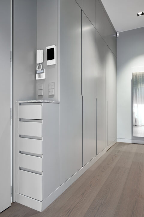 Eingangsbereich mit Einbauten in grauen Fronten und integrierten Schubladen.