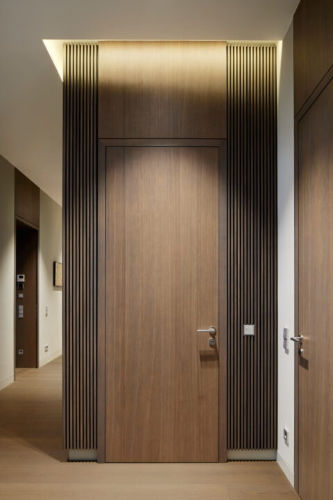 Flurbereich mit raumhohen Holztüren und vertikalen Lamellenpaneelen.