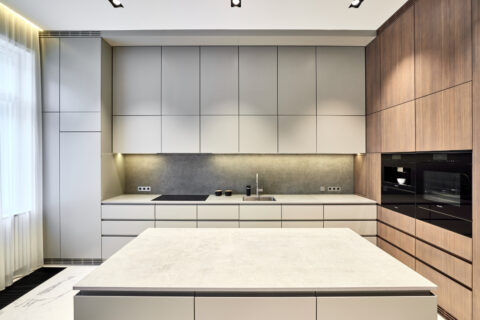 Küche mit zentraler Kücheninsel, grauen Fronten und Holzakzenten.